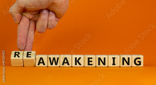 Reawakening symbol. Businessman turns cubes and changes the word 'awakening' to 'reawakening'. Beautiful orange background, copy space. Business and reawakening or awakening concept.