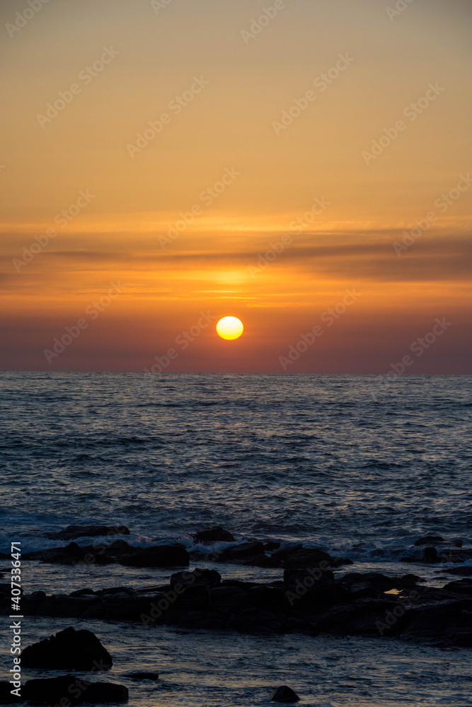 水平線に沈む夕陽と波
