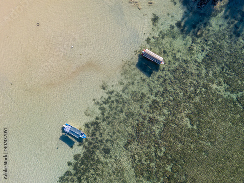 Aerial photography of fishing boats on tropical island ocean with clear sea water and reefs