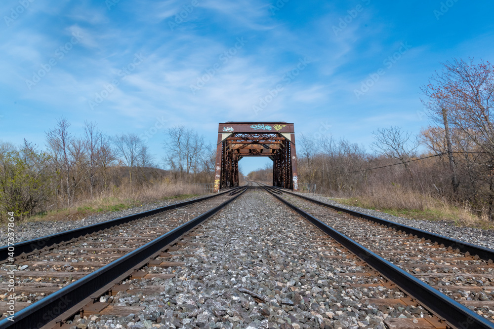 Fototapeta premium An old abandoned bridge, once part of the Grand Trunk Railway, sits in the middle of an overgrown field on a bright sunny day near Welland, Ontario.