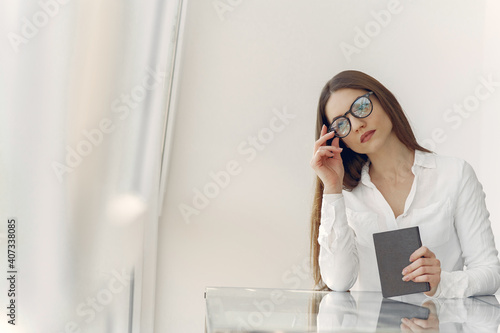 Girl in a office. Woman in a white shirt. Lady use the notebook.