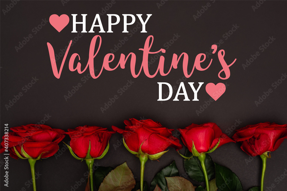 Top view of red roses near happy valentines day lettering on black Top view of red roses near happy valentines day lettering on black