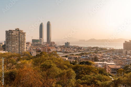 Xiamen city skyline with modern buildings, old town and sea at dusk