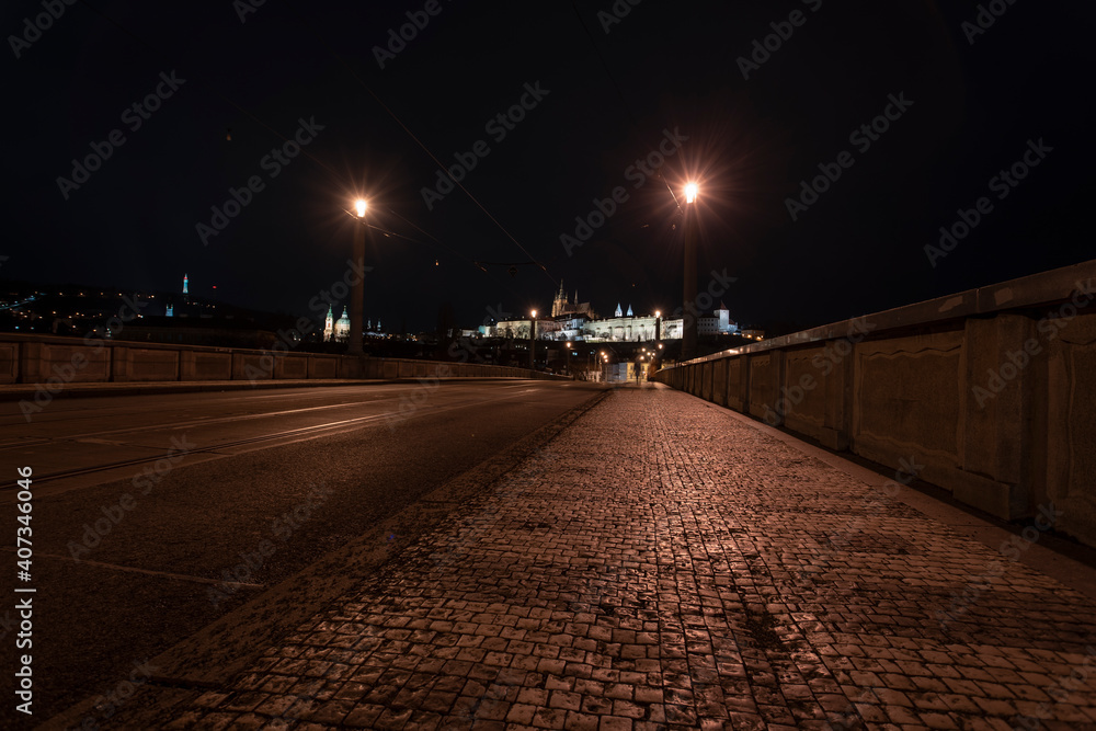 .tracks for the tram on the road and in the background Prague Castle in the center of Prague and light from the street lights