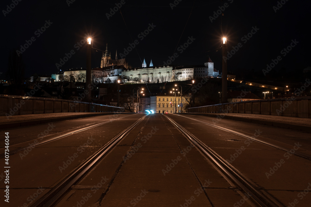 .tracks for the tram on the road and in the background Prague Castle in the center of Prague and light from the street lights .tracks for the tram on the road and in the background Prague Castle in the center of Prague and light from the street lights
