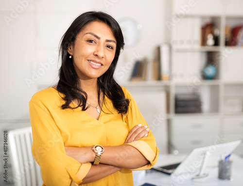 Fotografie, Tablou Happy smiling Latin American businesswoman standing in office with arms crossed