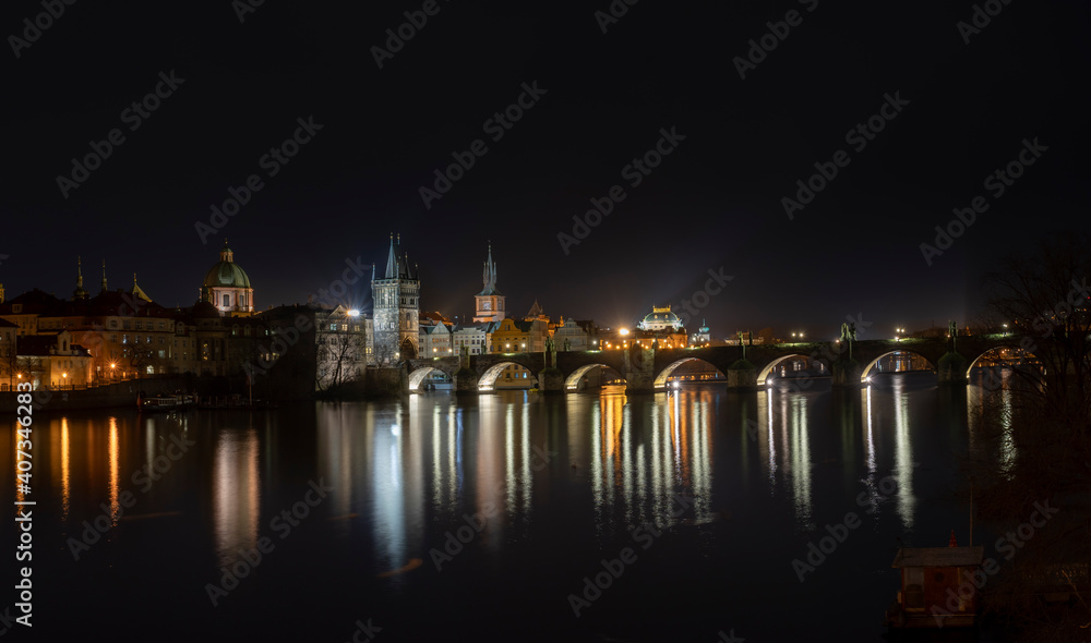 .panoramic view of Charles Bridge and illuminated street lights and the surrounding old architecture in the center of Prague in the Czech Republic at night