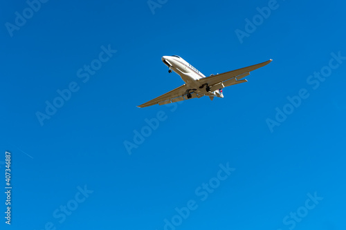 Private jet plane flies in the blue sky.