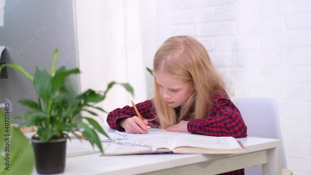 4k Blonde schoolgirl studying at home doing school homework. Training books and notebooks on table. Distance learning online education 4k Blonde schoolgirl studying at home doing school homework. Training books and notebooks on table. Distance learning online education