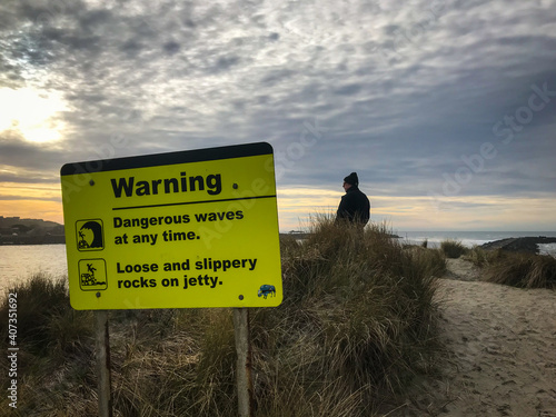 Warning sign dangerous waves. Male tourist in scene.  photo