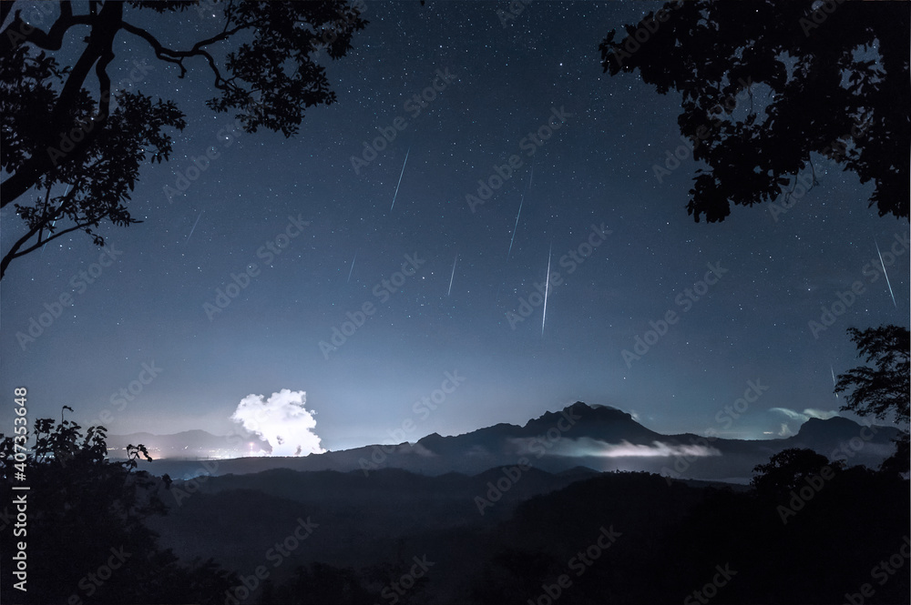 Naklejka premium Geminids meteor shower in the night sky with the mist on hill, Long Exposure, Mae Moh Lampang Thailand.