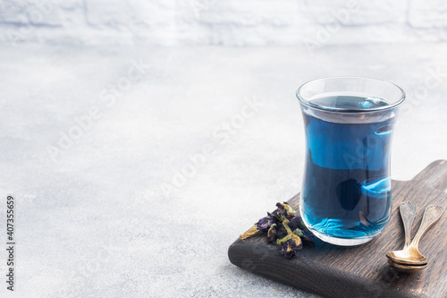 Thai blue tea anchan of buds klitoria Ternate in a glass cup, grey concrete background. Copy space.