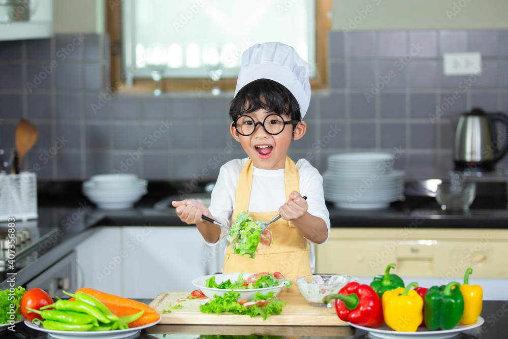 Boy with chef hat preparing vegetable salad in the kitchen Boy with chef hat preparing vegetable salad in the kitchen