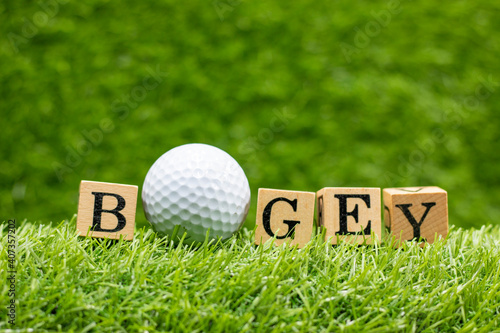 Golf bogey with golf ball and word is on green grass background. in golf, the act of getting the ball into the hole in one shot more than par the expected number for that hole. photo