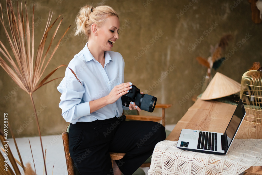 Woman holding digital camera and looking at laptop screen