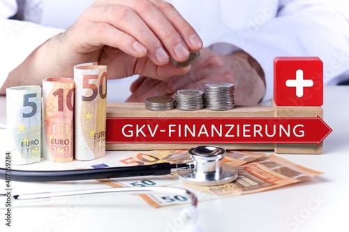 GKV-Finanzierung. Arzt stapelt Geld Münzen auf einen Geldstapel. Text mit Begriff auf Pfeil Symbol (rot). Geldscheine & Stethoskop