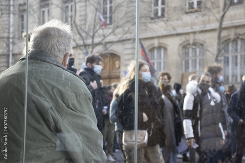 Une personne âgé regarde passer la manifestation étudiante pour la réouverture des universités et l'augmentation des aides suite à la crise sanitaire, le long du jardin du Luxembourg.
