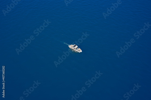 Drone view of a boat. Lonely boat mooring on the water. Top view of a white boat in the blue sea. luxury motor boat. Aerial view of a yacht on blue water.