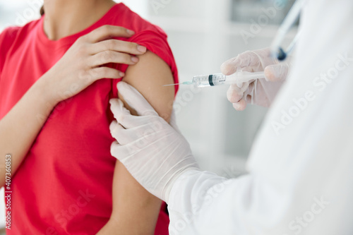 a doctor injects a vaccine into the shoulder of a woman patient close-up