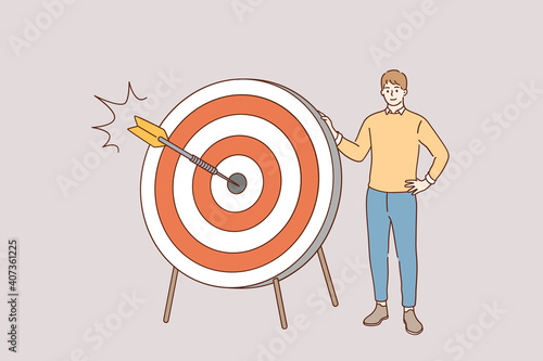 Marketing strategy and purpose concept. Young positive man cartoon character standing holding dart board with direct hit on target meaning goal achievement and success vector illustration