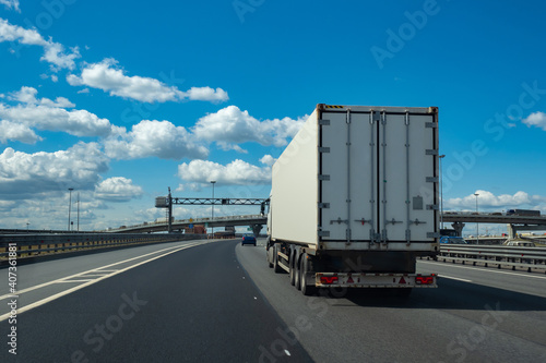 Truck is driving on a highway. Lorry with white trailer rear view. Transportation of goods with lorry. Road freight transportation. Concept - work as a truck driver. Truck business career