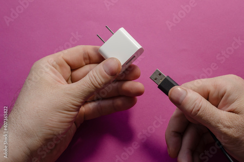 DC adapter and USB data cable in male hands.
