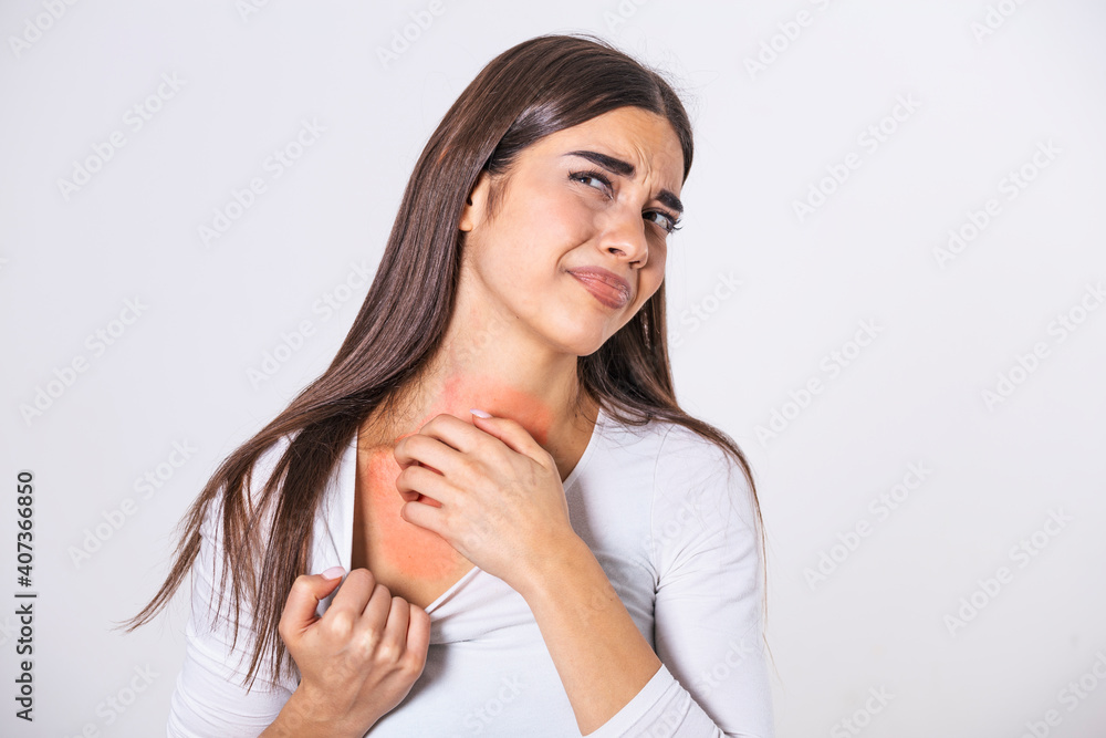 Young woman scratching her neck due to itching on a gray background. Female has an itching neck. The concept of allergy symptoms and healthcare Young woman scratching her neck due to itching on a gray background. Female has an itching neck. The concept of allergy symptoms and healthcare