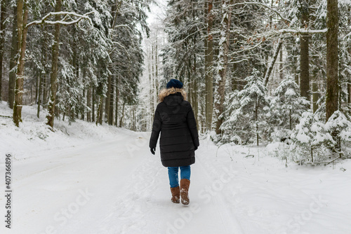 Woman walking on a winter forest park,back view. outdoors shot. © ARVD73