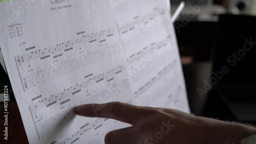 Male index finger reading sheet music on a music stand photo