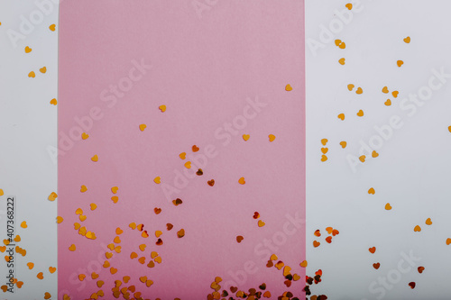 Golden glitters in shape of heart on pink piece of paper. Saint Valentine's Day card with space for text.