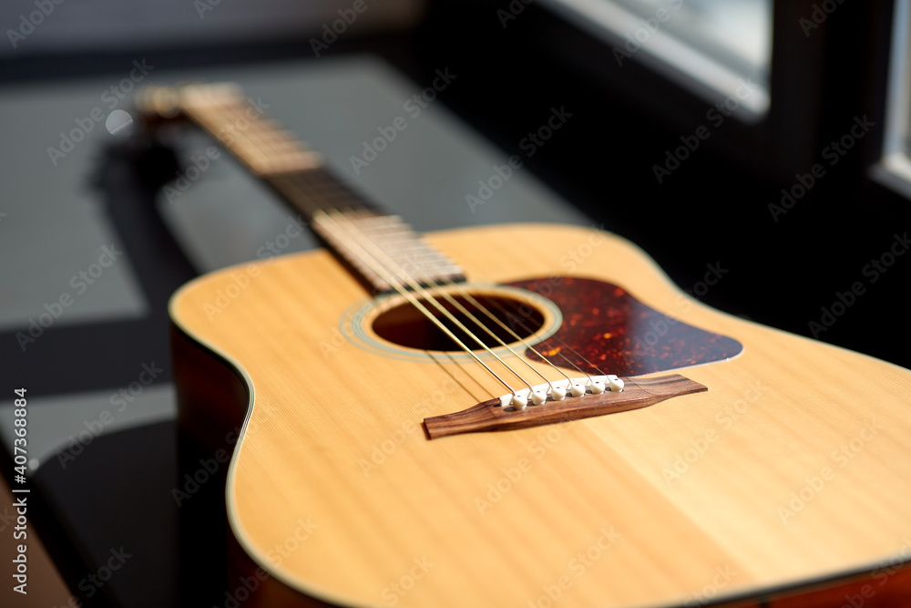leisure, music and musical instruments concept - close up of acoustic guitar on window sill leisure, music and musical instruments concept - close up of acoustic guitar on window sill