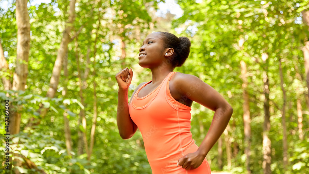 fitness, sport and healthy lifestyle concept - happy smiling young african american woman running in forest fitness, sport and healthy lifestyle concept - happy smiling young african american woman running in forest