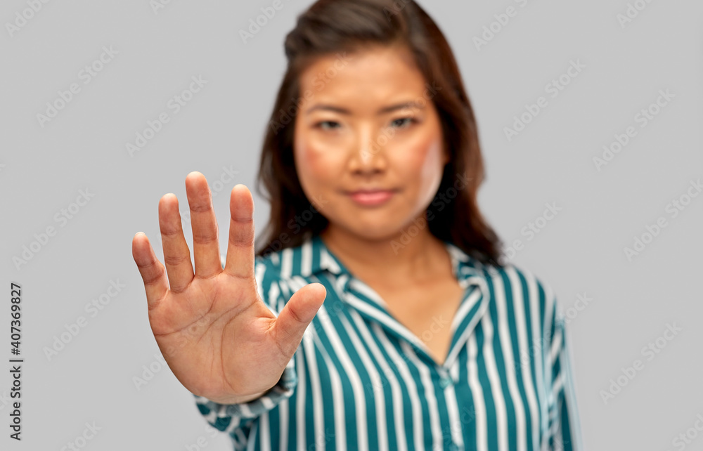 people, prohibition and rejection concept - close up of asian young woman showing stop gesture over grey background people, prohibition and rejection concept - close up of asian young woman showing stop gesture over grey background
