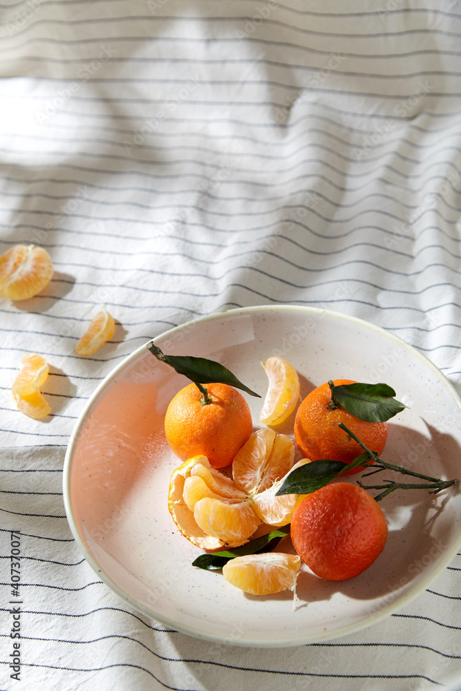 food, healthy eating and fruits concept - close up of mandarins on plate over drapery food, healthy eating and fruits concept - close up of mandarins on plate over drapery