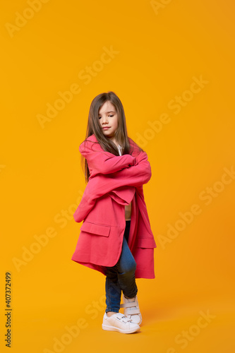 Serious young girl in oversized jacket with crossed hands