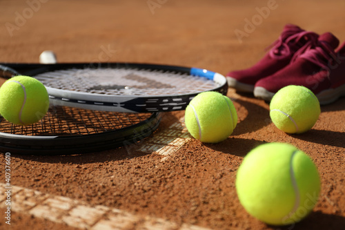 Tennis balls, rackets and shoes on clay court, closeup