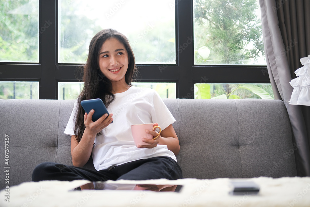 Happy young woman sitting on sofa and using mobile phone. Happy young woman sitting on sofa and using mobile phone.
