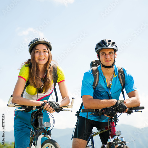 Fototapeta Naklejka Na Ścianę i Meble -  ACTIVE Young couple biking on a forest road in mountain on a spring day