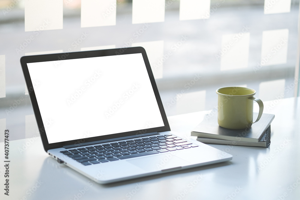 Fototapeta premium Mock up laptop computer with blank screen, coffee cup and notebook on modern workspace.