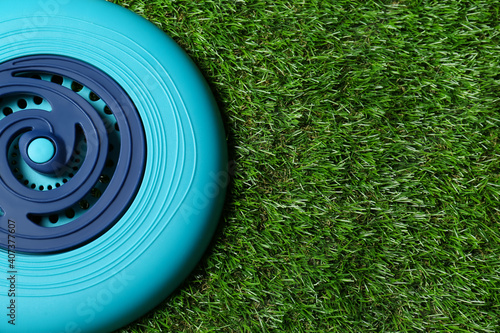Light blue plastic frisbee disk on green grass, top view. Space for text photo