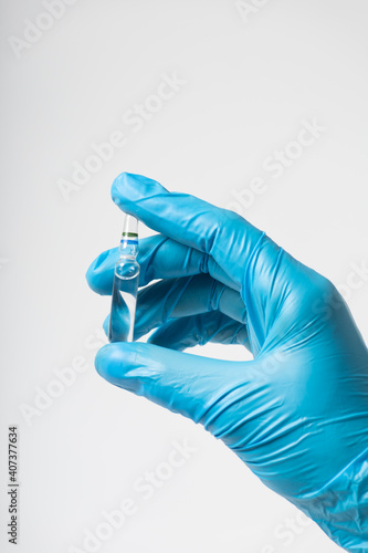 Vaccine ampoule in hand in a medical glove