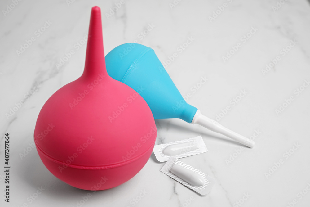 Different enemas and suppositories on white table. Medical treatment Different enemas and suppositories on white table. Medical treatment