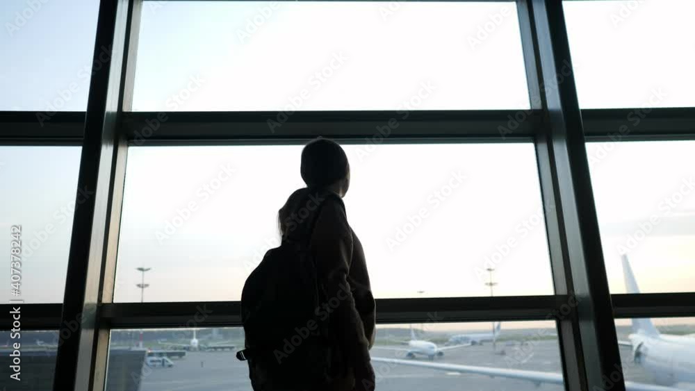 Young woman with a backpack walks past the panoramic window at the airport. Young woman with a backpack walks past the panoramic window at the airport.