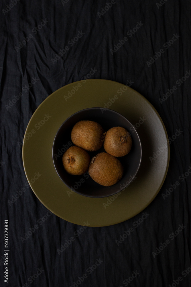 Kiwis on a plate isolated on dark black background. Still life photography. Food photography. Sliced kiwi on a plate. Kiwis on a plate isolated on dark black background. Still life photography. Food photography. Sliced kiwi on a plate.