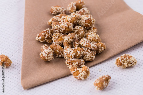 Cashew nuts in sesame seeds with honey on paper.