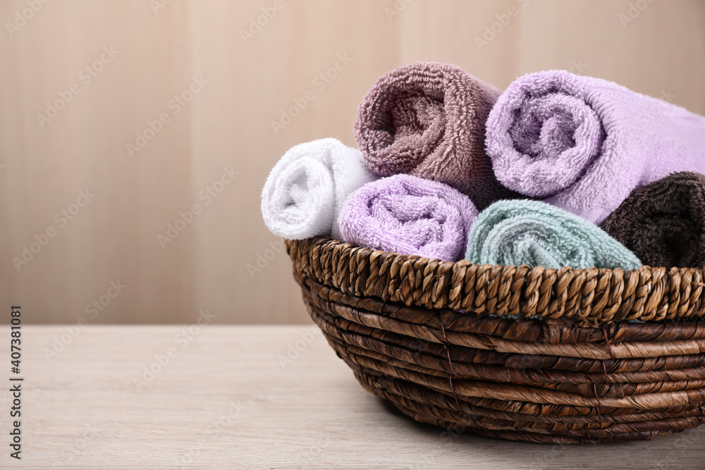Rolled soft towels in wicker basket on wooden table. Space for text Rolled soft towels in wicker basket on wooden table. Space for text