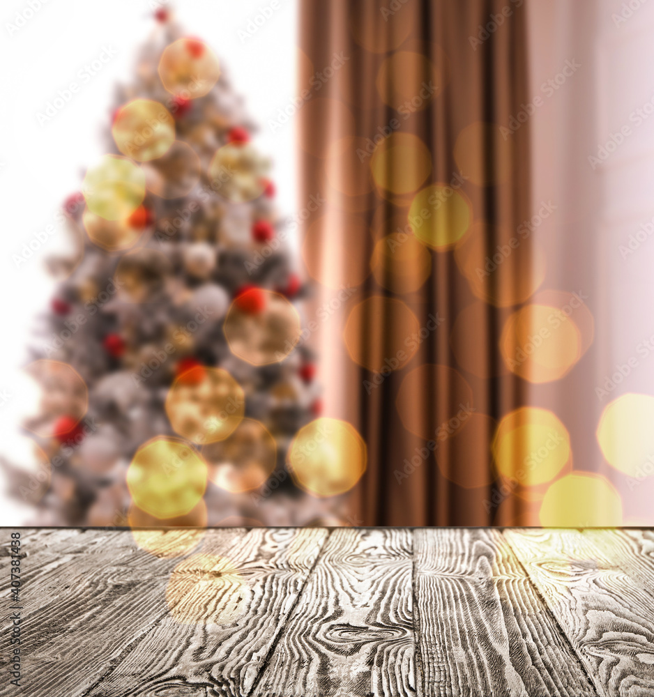 Empty wooden surface and blurred view of Christmas tree in room, space for text. Interior design
