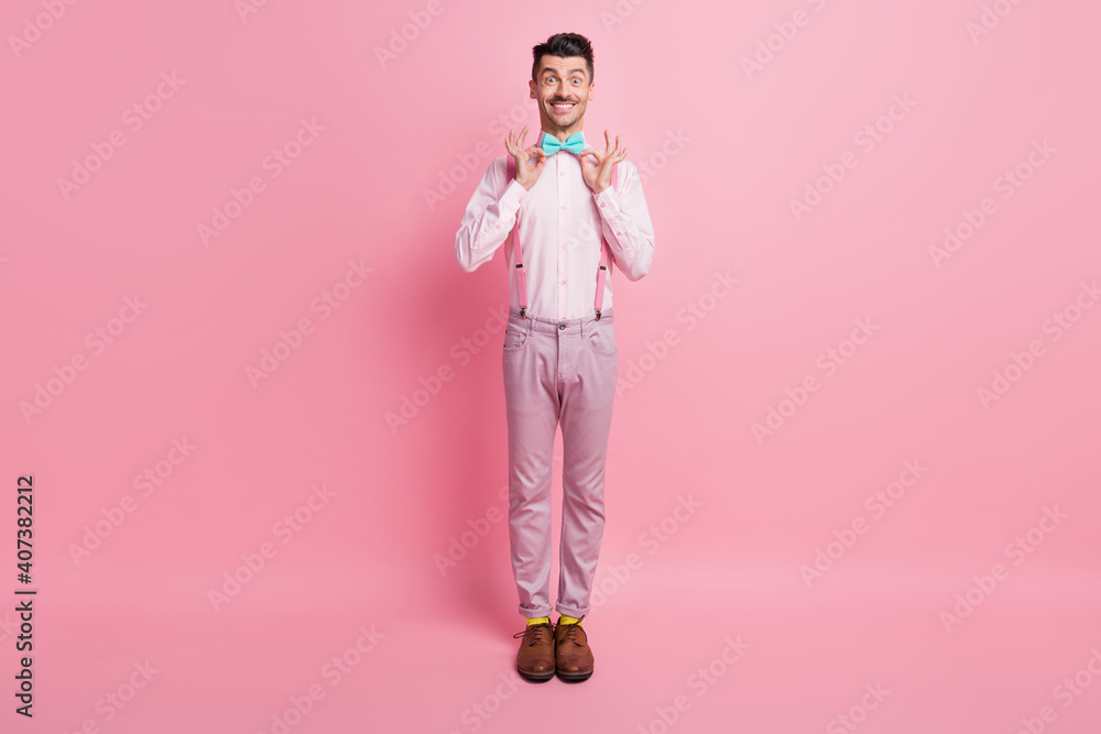 Photo portrait full body view of excited cheerful guy adjusting bowtie isolated on pastel pink colored background Photo portrait full body view of excited cheerful guy adjusting bowtie isolated on pastel pink colored background
