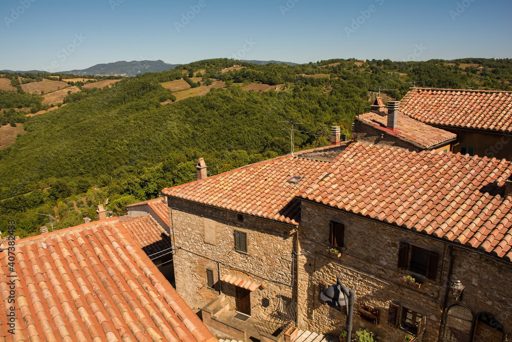 The late summer landscape near the historic medieval village of Semproniano in Grosseto Province, Tuscany, Italy, seen from over the village's rooftops
