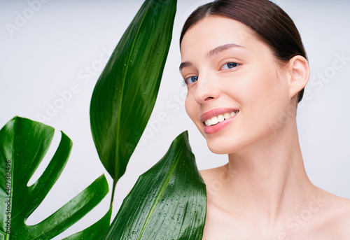 Delicate smiling beauty surrounded by green tropical plants.